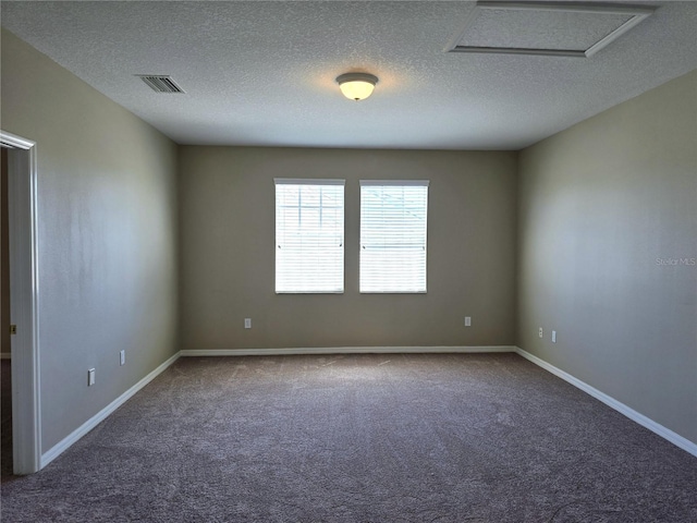 spare room featuring visible vents, attic access, carpet flooring, a textured ceiling, and baseboards