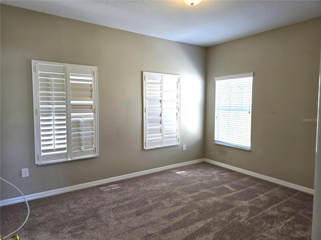 unfurnished room featuring dark carpet and baseboards