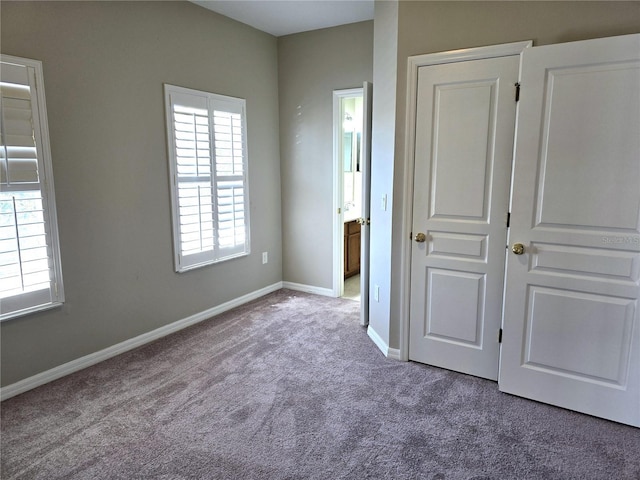 unfurnished bedroom with carpet floors, ensuite bath, and baseboards