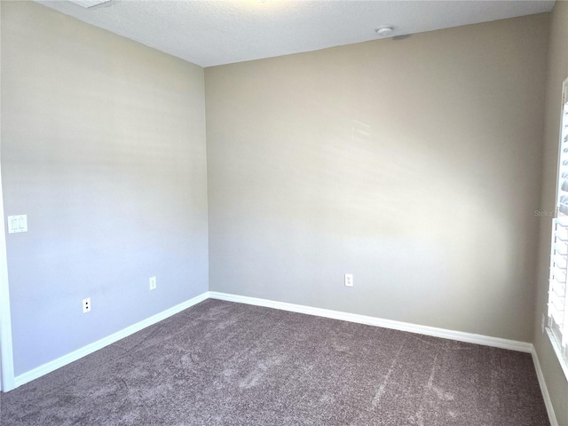 spare room with a textured ceiling, baseboards, and carpet flooring