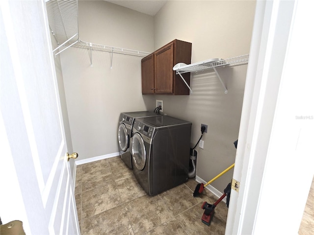 washroom featuring washing machine and clothes dryer, cabinet space, and baseboards