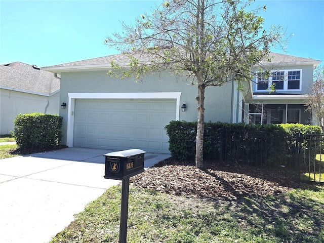 view of front of house featuring driveway, roof with shingles, an attached garage, fence, and stucco siding