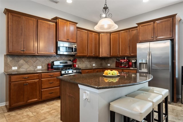 kitchen featuring stainless steel appliances, a kitchen island, a kitchen breakfast bar, decorative backsplash, and decorative light fixtures