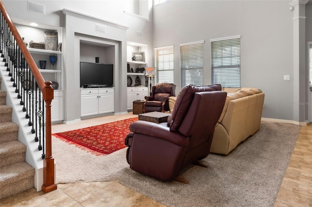 living room with light tile patterned flooring, a high ceiling, visible vents, built in features, and stairway