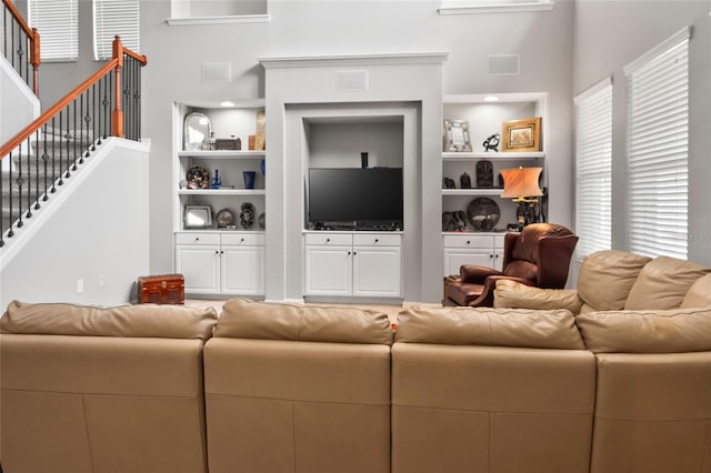 living room featuring built in shelves, stairway, and visible vents