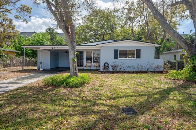 view of front of property featuring an attached carport, fence, driveway, stucco siding, and a front lawn