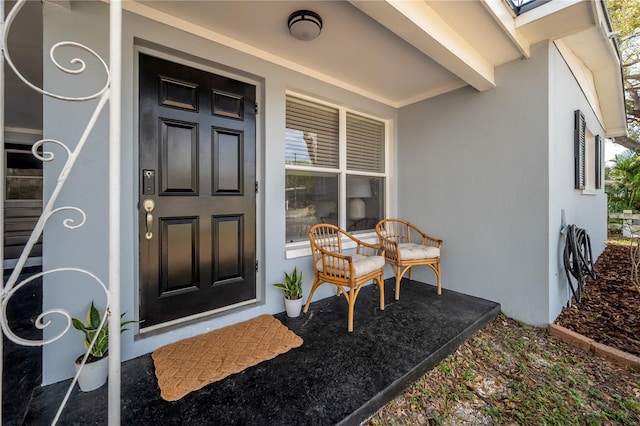 entrance to property with a porch and stucco siding