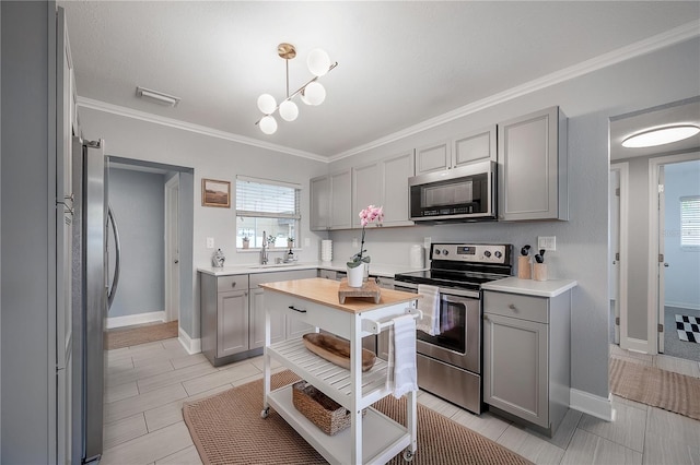 kitchen with appliances with stainless steel finishes, light countertops, a sink, and gray cabinetry