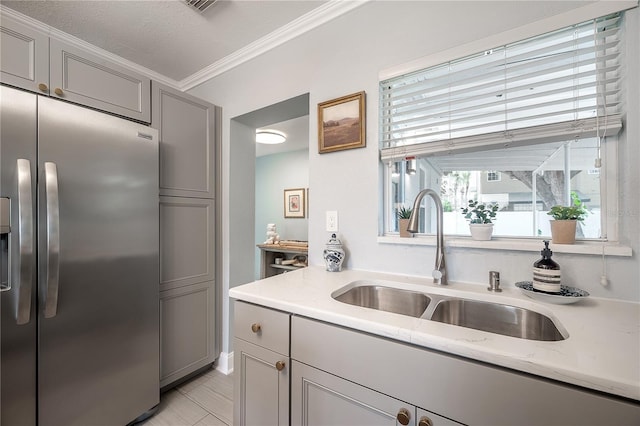 kitchen with gray cabinets, a sink, stainless steel refrigerator with ice dispenser, and light stone countertops