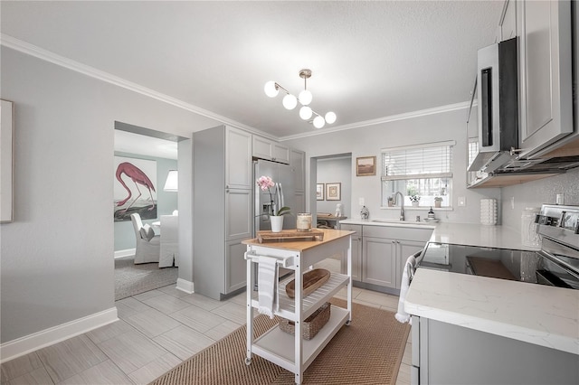 kitchen with stainless steel appliances, gray cabinets, a sink, and ornamental molding