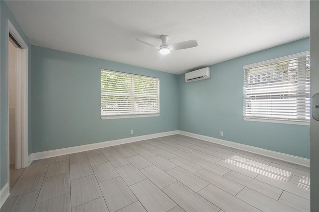 unfurnished room featuring a wall unit AC, plenty of natural light, and baseboards