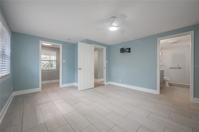 unfurnished bedroom featuring ceiling fan, ensuite bathroom, and baseboards