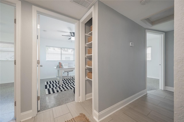 hall with attic access, carpet, visible vents, and baseboards