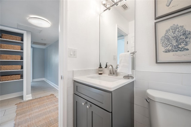 half bathroom featuring visible vents, vanity, and toilet