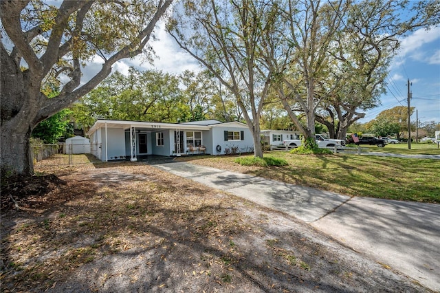 view of front of property with an attached carport, covered porch, fence, concrete driveway, and a front yard