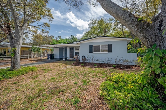 view of front facade featuring aphalt driveway, an attached carport, and stucco siding