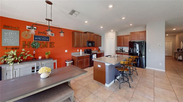 kitchen featuring light tile patterned floors, visible vents, a breakfast bar, black appliances, and a sink