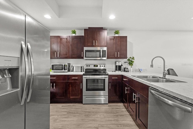 kitchen featuring stainless steel appliances, light countertops, a sink, and light wood-style flooring