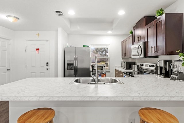 kitchen featuring stainless steel appliances, recessed lighting, light countertops, and a kitchen breakfast bar