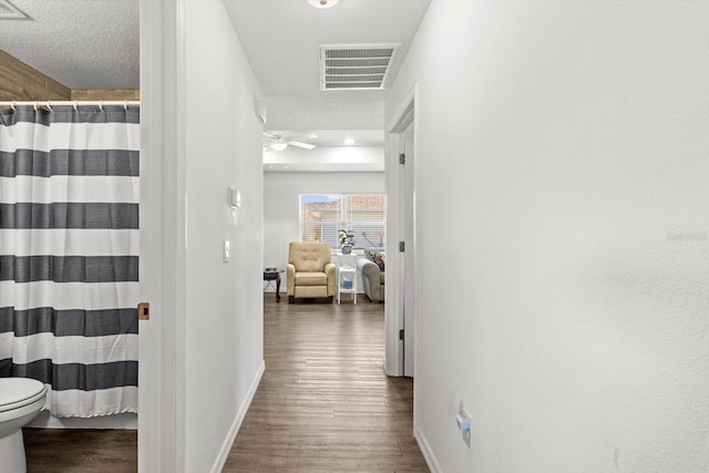 corridor with visible vents, baseboards, and wood finished floors