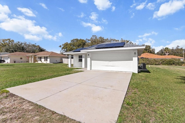 single story home featuring concrete driveway, an attached garage, a front lawn, and solar panels