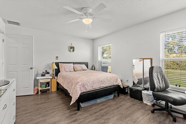 bedroom with a textured ceiling, visible vents, and wood finished floors