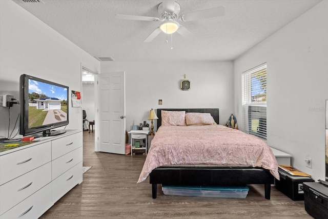 bedroom featuring visible vents, a textured ceiling, a ceiling fan, and wood finished floors