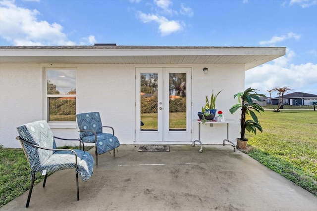 entrance to property featuring a yard, a patio, french doors, and stucco siding