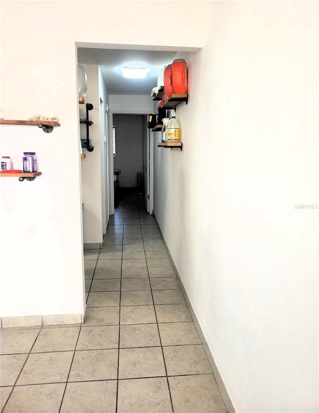 hall featuring baseboards and light tile patterned floors