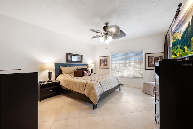 bedroom with ceiling fan, light tile patterned floors, baseboards, and a textured ceiling