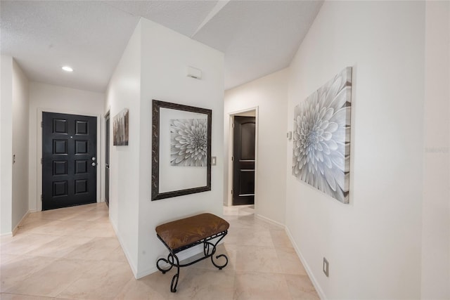 hallway with baseboards and a textured ceiling