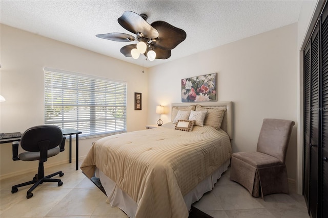 bedroom with a closet, a textured ceiling, light tile patterned flooring, and a ceiling fan