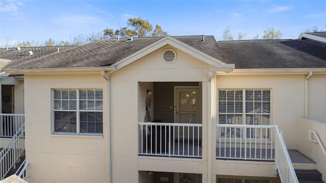 property entrance featuring stucco siding and roof with shingles