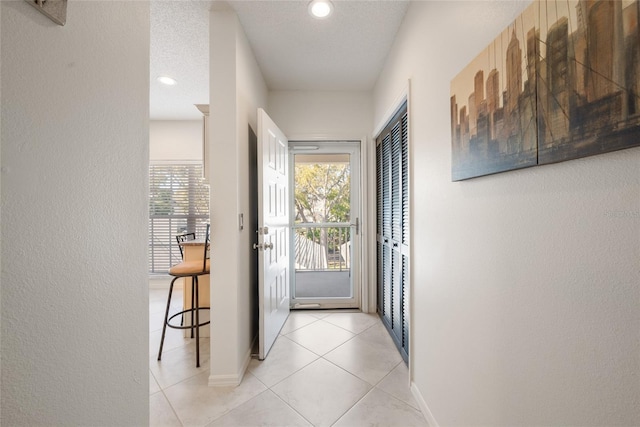 entryway with light tile patterned floors, baseboards, recessed lighting, a textured ceiling, and a textured wall