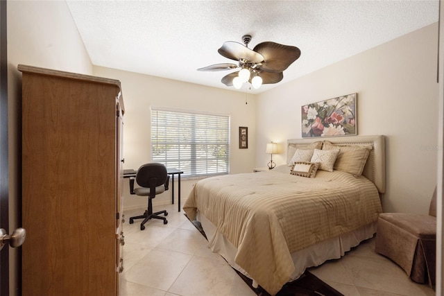 bedroom featuring ceiling fan, light tile patterned floors, and a textured ceiling