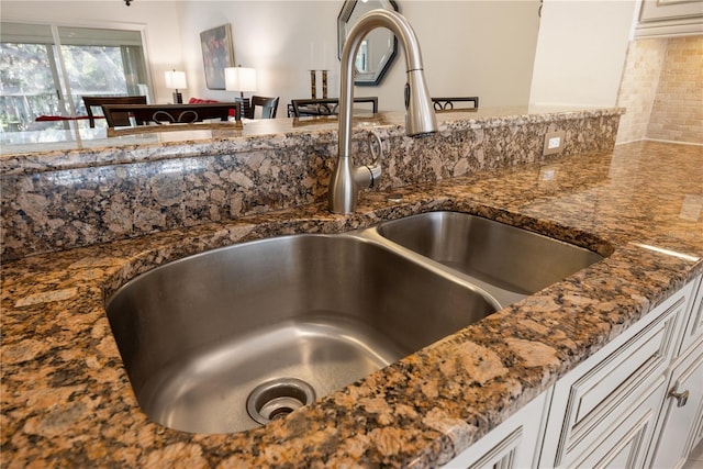 interior details with backsplash, dark stone counters, and a sink