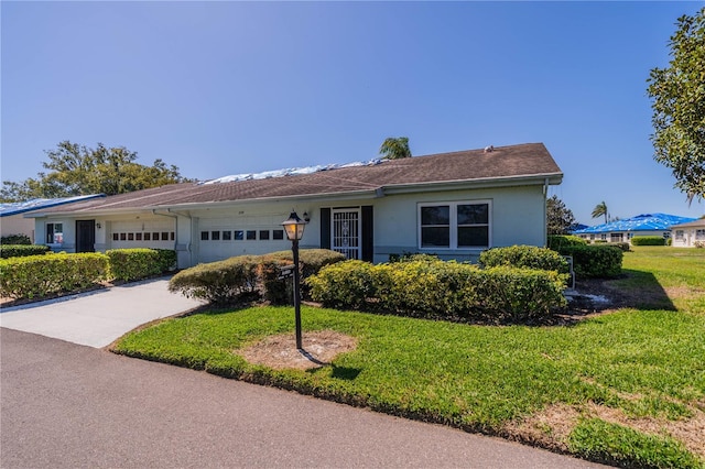 ranch-style home with a garage, driveway, a front lawn, and stucco siding