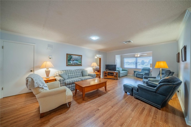 living room featuring visible vents, crown molding, a textured ceiling, and light wood-type flooring