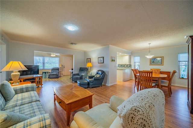 living room featuring visible vents, crown molding, and light wood-type flooring