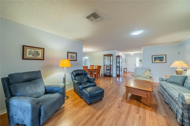 living room featuring crown molding, visible vents, and light wood finished floors