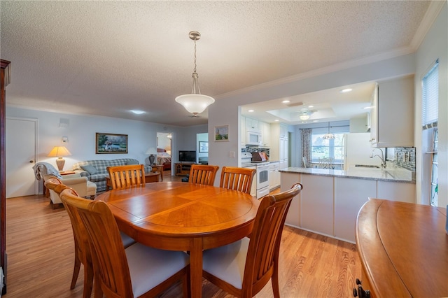 dining area with recessed lighting, light wood-style floors, ornamental molding, and a textured ceiling