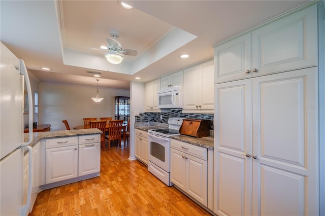 kitchen featuring light wood-type flooring, backsplash, white cabinetry, white appliances, and a raised ceiling