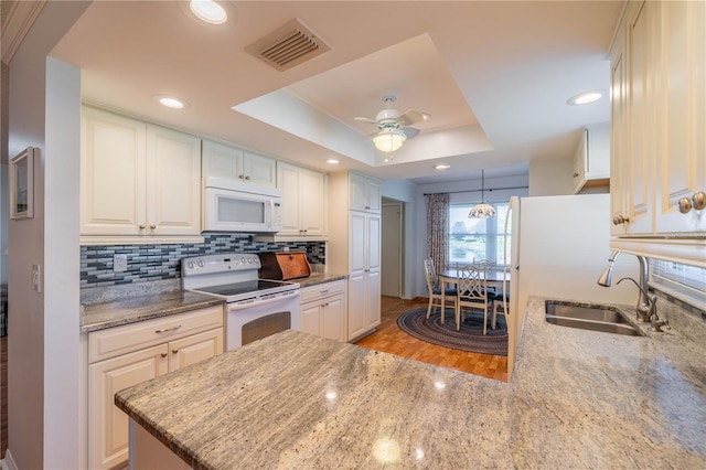 kitchen featuring visible vents, white appliances, a raised ceiling, and tasteful backsplash