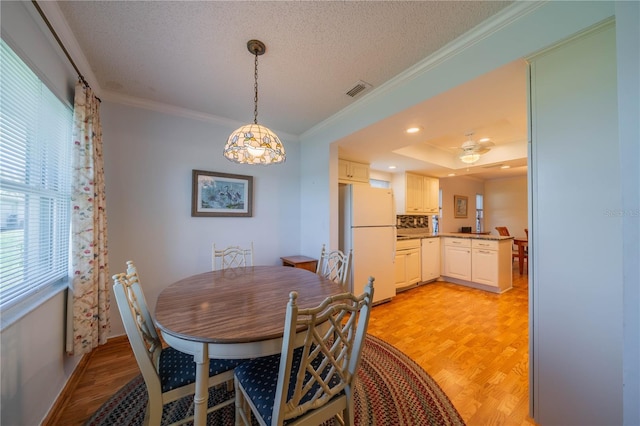 dining area featuring visible vents, light wood finished floors, and ornamental molding