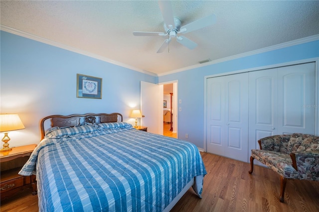 bedroom featuring visible vents, wood finished floors, a closet, and ornamental molding