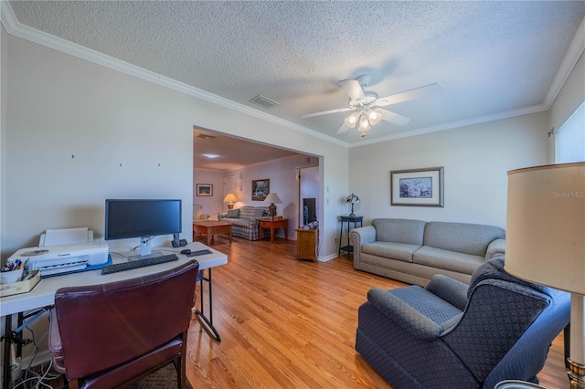 home office with a ceiling fan, visible vents, light wood finished floors, and ornamental molding