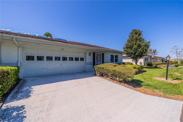 ranch-style home featuring stucco siding, an attached garage, driveway, and a front yard