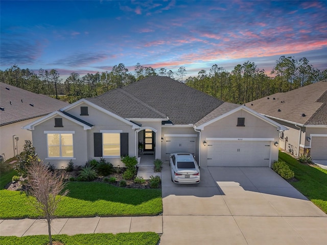 ranch-style house with an attached garage, driveway, a shingled roof, and stucco siding