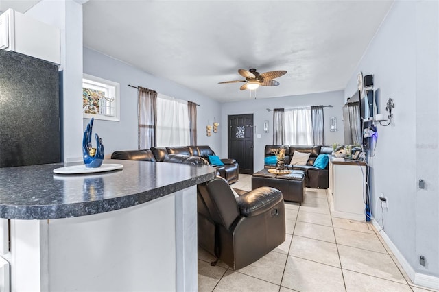 living room with light tile patterned floors, a ceiling fan, and baseboards