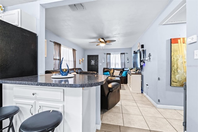 kitchen with light tile patterned flooring, visible vents, white cabinetry, open floor plan, and dark countertops